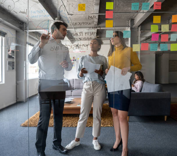 Latin American business team discussing a marketing strategy in a meeting at the office and writing ideas on a glass board